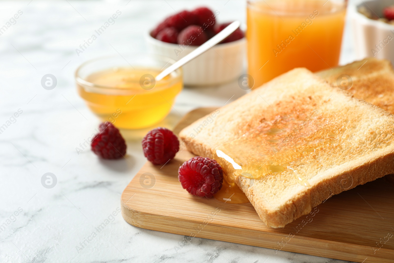 Photo of Delicious breakfast with toasted bread, honey and berries on white marble table, closeup