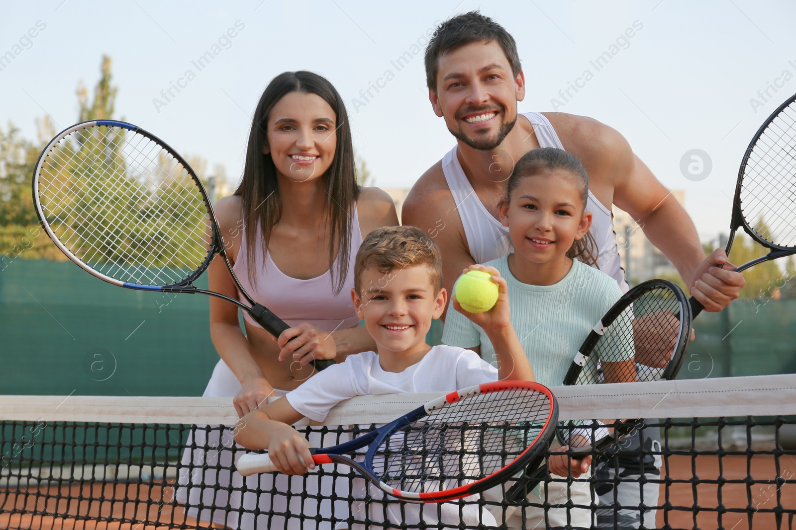 Photo of Happy family with tennis rackets on court outdoors