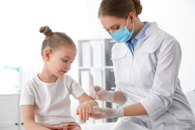 Photo of Doctor applying cream onto skin of little girl with chickenpox in clinic. Varicella zoster virus