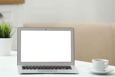 Laptop with blank screen on table indoors. Space for text