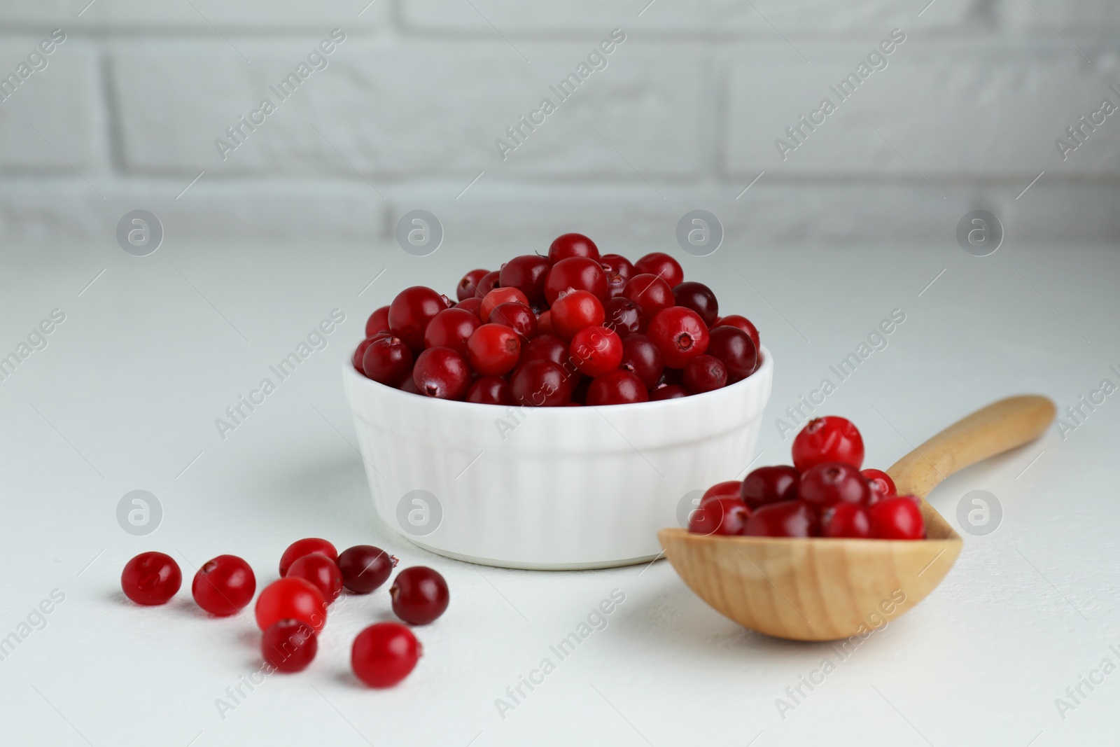 Photo of Cranberries in bowl and spoon on white table