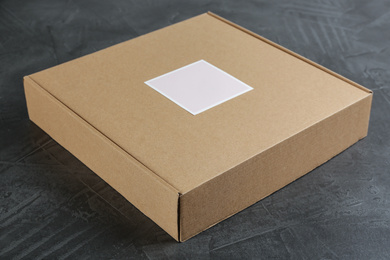 Photo of Closed cardboard box on grey stone table, closeup