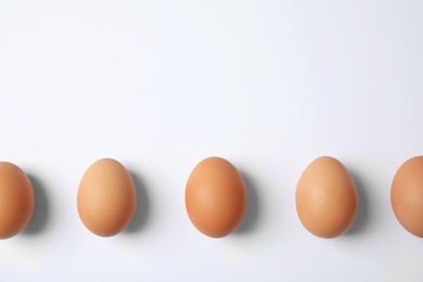 Photo of Raw chicken eggs on white background, top view