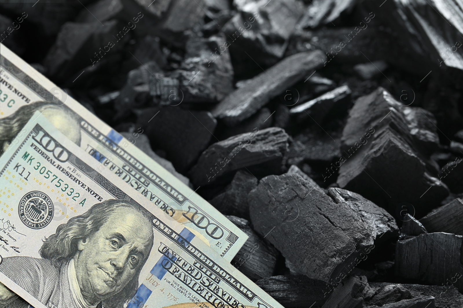 Image of Dollar banknotes on pieces of coal, closeup. Resource price