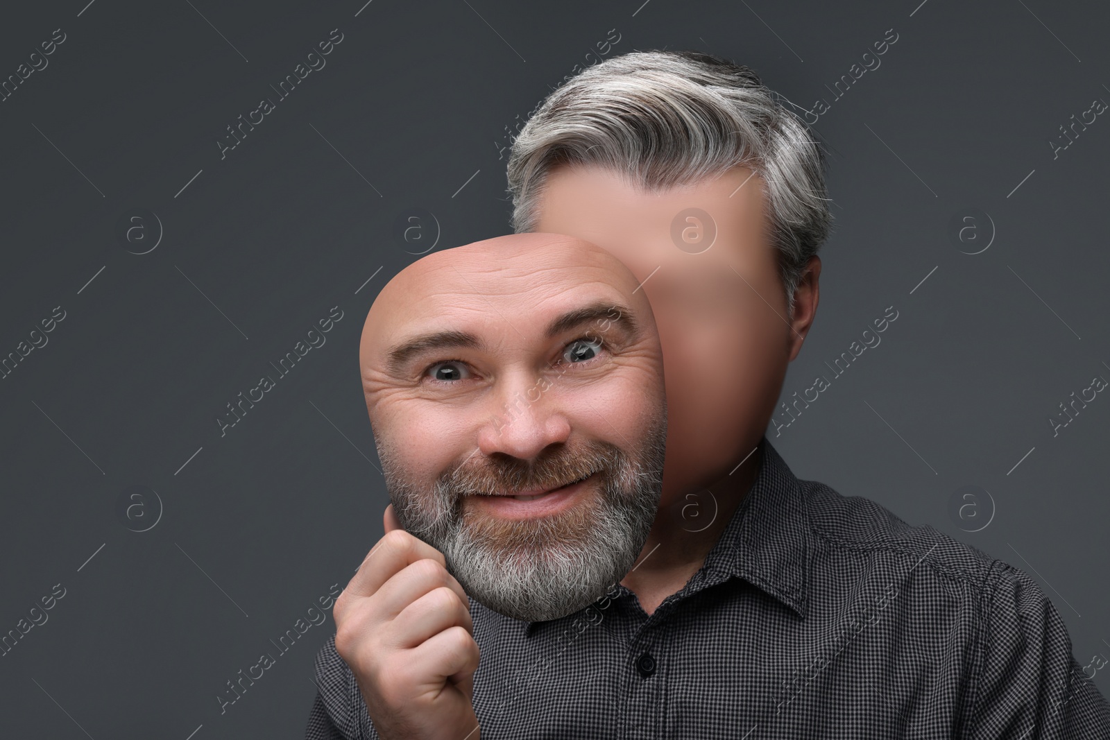 Image of Faceless man holding his face mask showing emotion on grey background. Personality crisis.