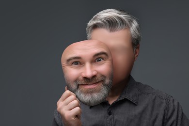 Image of Faceless man holding his face mask showing emotion on grey background. Personality crisis.