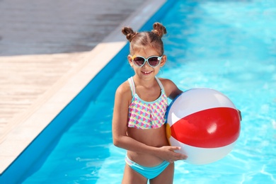 Photo of Cute little girl with inflatable ball in swimming pool