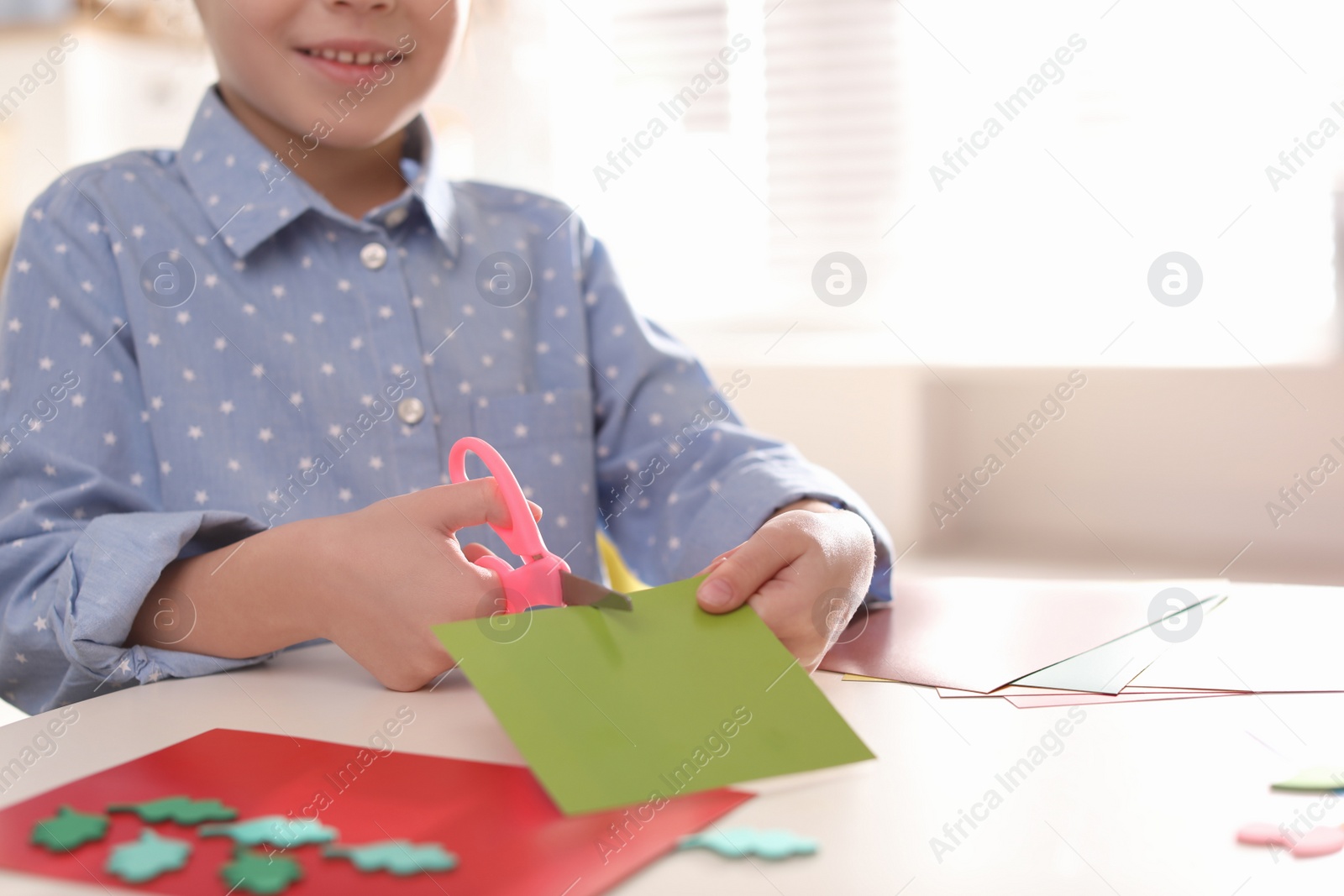 Photo of Little girl making greeting card at table indoors, closeup with space for text. Creative hobby
