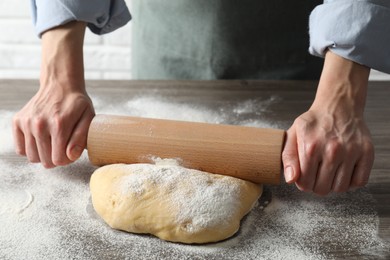 Photo of Woman rolling raw dough at table, closeup