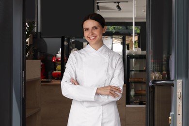 Photo of Happy baker in uniform at door of her cafe