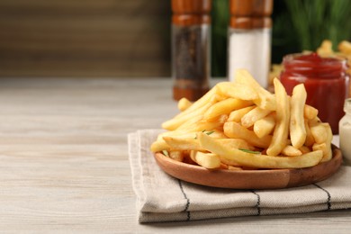 Photo of Delicious french fries served with sauces on light wooden table. Space for text