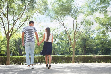 Lovely couple walking together in park on sunny day. Space for text