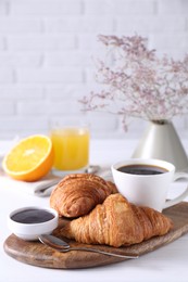 Photo of Tasty breakfast. Cup of coffee, jam and croissants on white wooden table