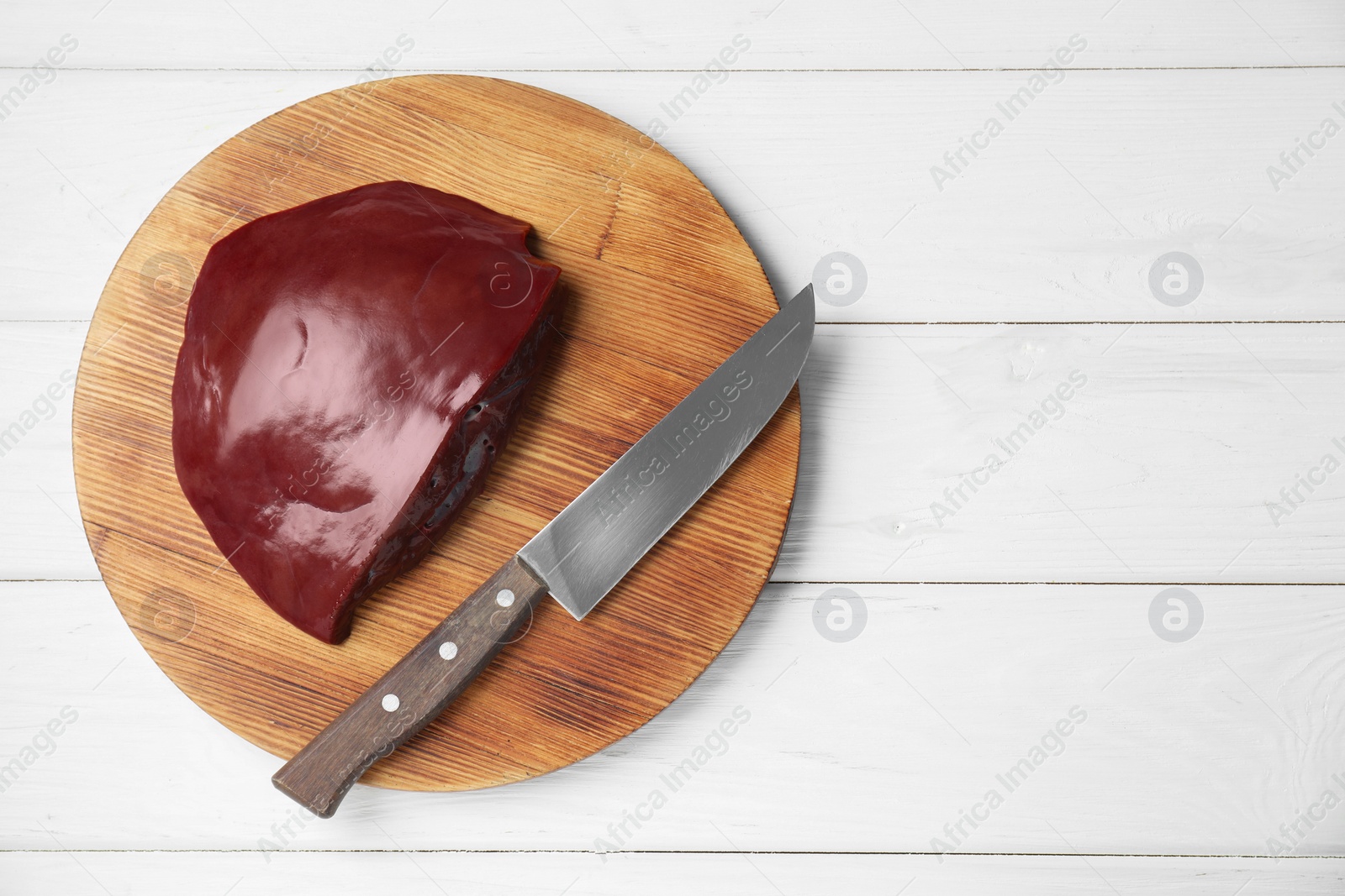 Photo of Piece of raw beef liver and knife on white wooden table, top view. Space for text