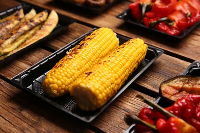 Photo of Plastic containers with different grilled meal on wooden table, closeup. Food delivery service