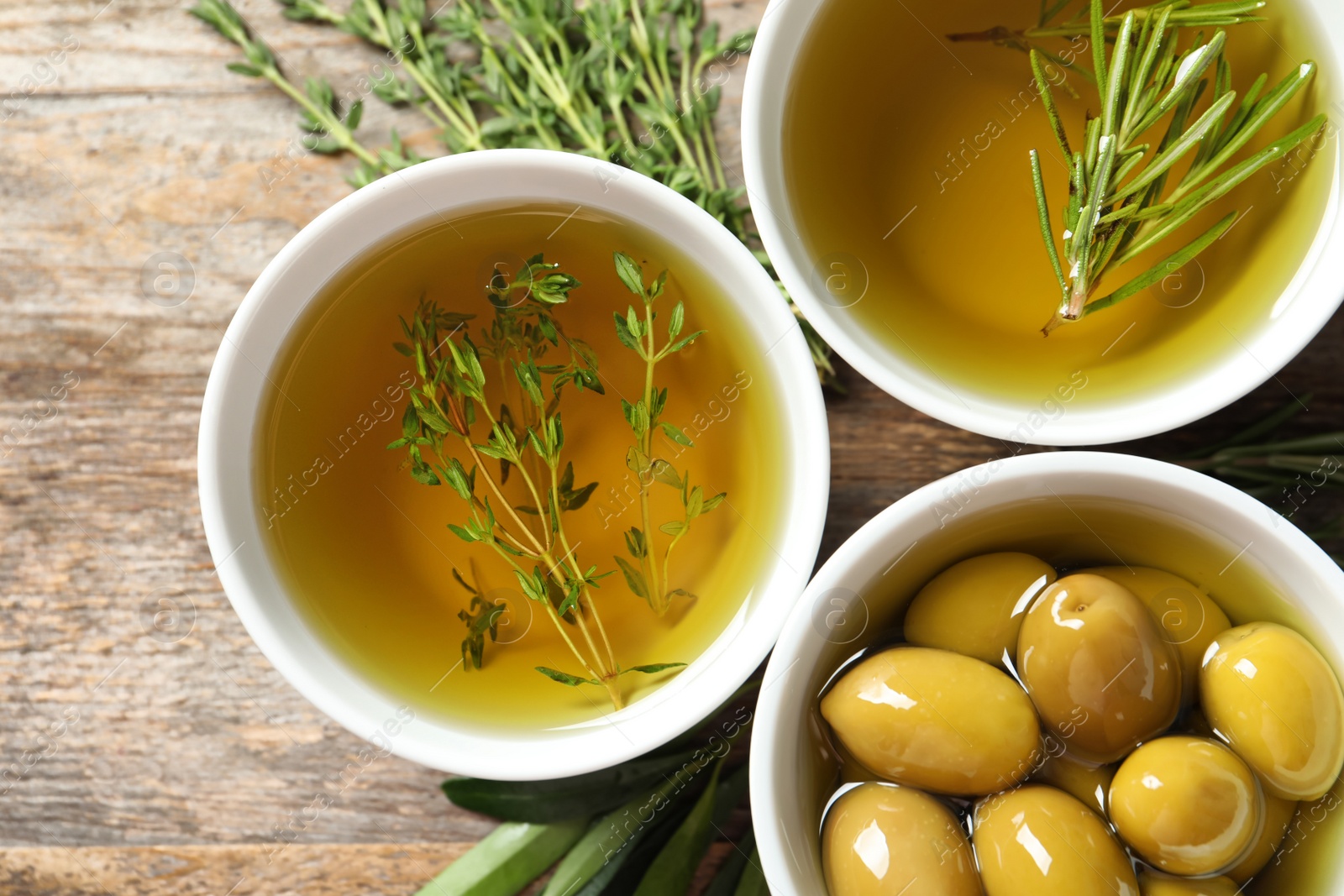 Photo of Beautiful composition with oil and ripe olives on wooden table, top view