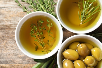 Beautiful composition with oil and ripe olives on wooden table, top view