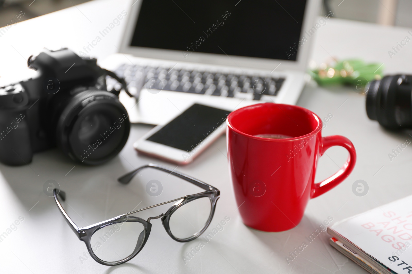 Photo of Blogger work space with cup of coffee and glasses on table indoors