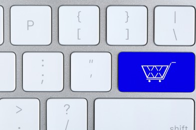 Online store. Blue button with shopping cart on computer keyboard, top view