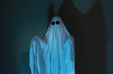 Photo of Creepy ghost. Woman covered with sheet in color light
