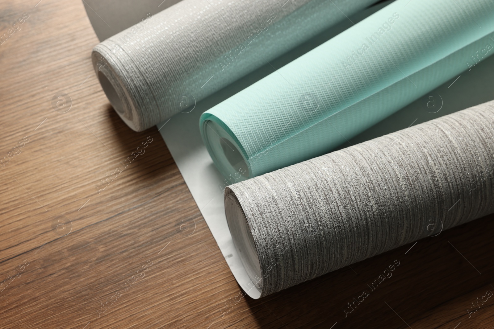 Photo of Different stylish wallpaper rolls on wooden table