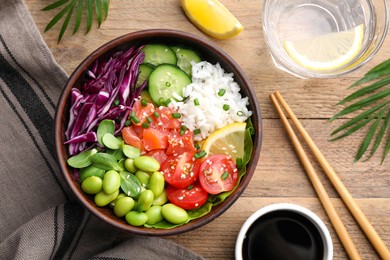 Photo of Poke bowl with salmon, edamame beans and vegetables on wooden table, flat lay
