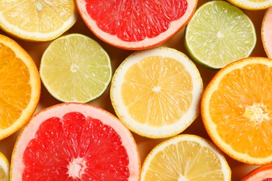 Photo of Different cut citrus fruits on beige table, flat lay