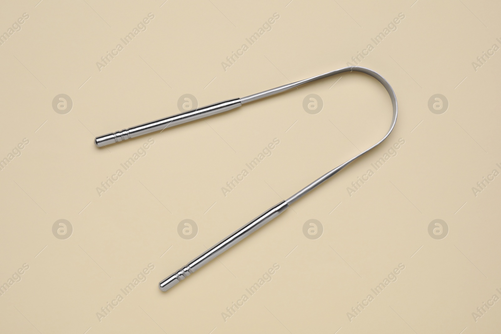 Photo of Metal tongue cleaner on beige background, top view