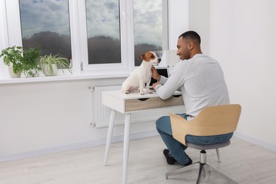 Young man with Jack Russell Terrier at desk in home office