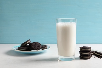 Glass of milk with chocolate cookies on table against color background. Space for text