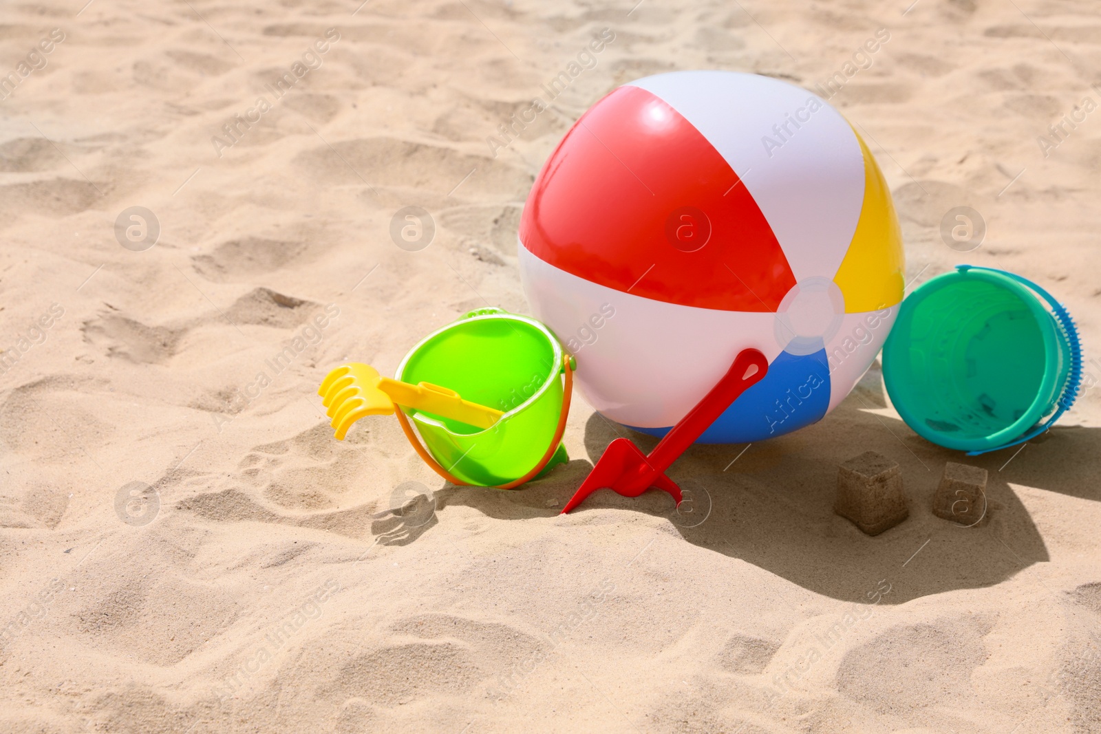 Photo of Different beach toys and inflatable ball on sand outdoors, space for text