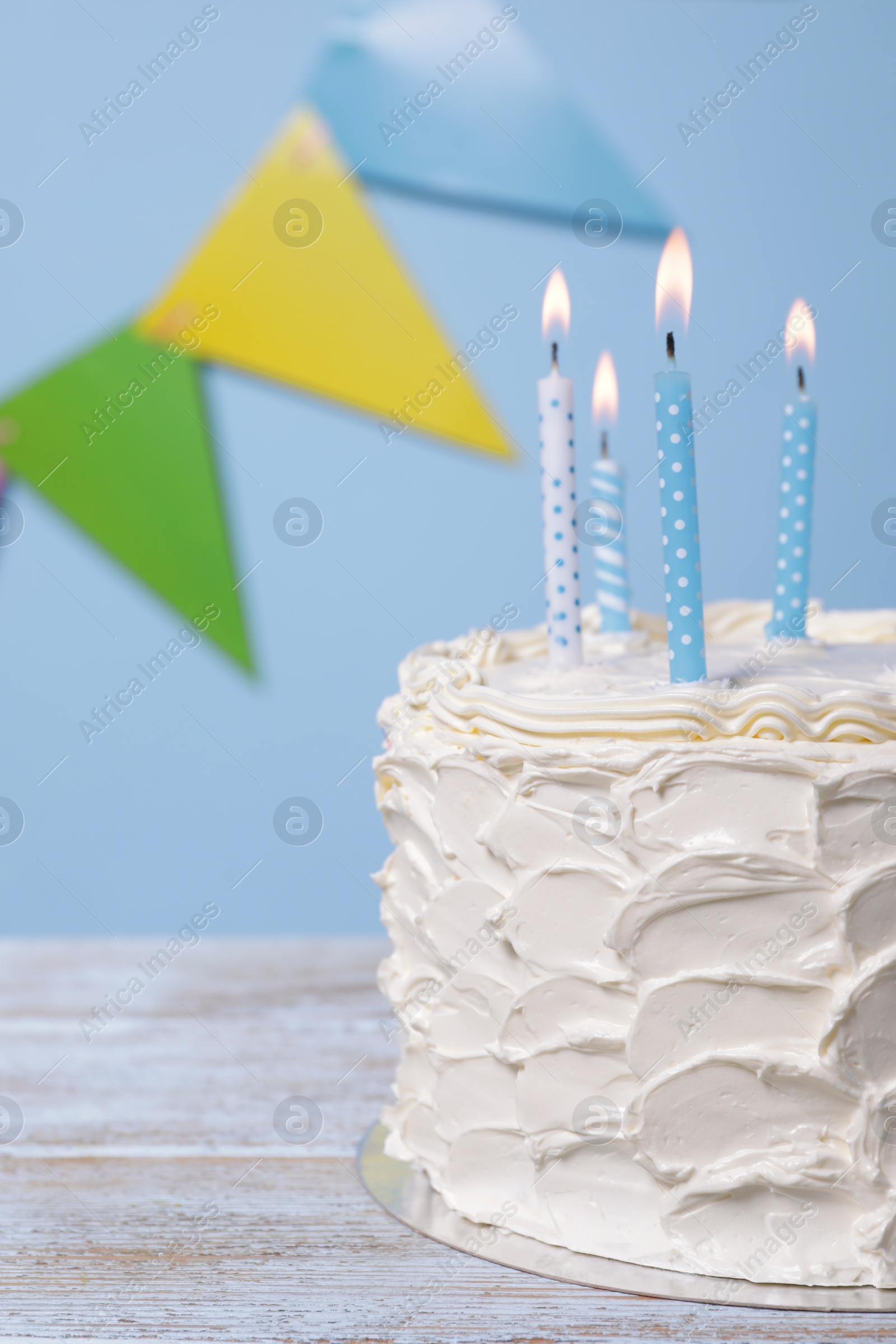 Photo of Delicious cake with burning candles and festive decor on wooden table, closeup