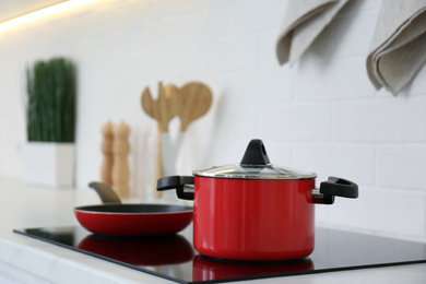 Red pot and frying pan on stove in kitchen