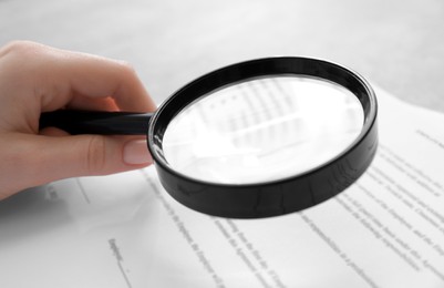 Photo of Woman looking at document through magnifier at table, closeup. Searching concept