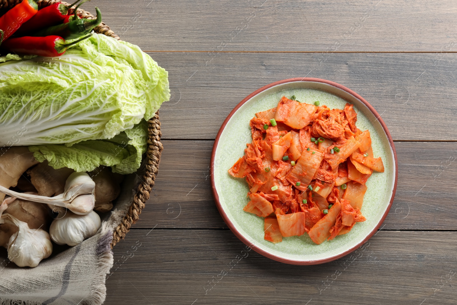 Photo of Delicious kimchi with Chinese cabbage and ingredients on wooden table, flat lay