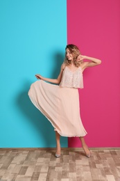 Photo of Young woman with beautiful long legs in stylish outfit near color wall