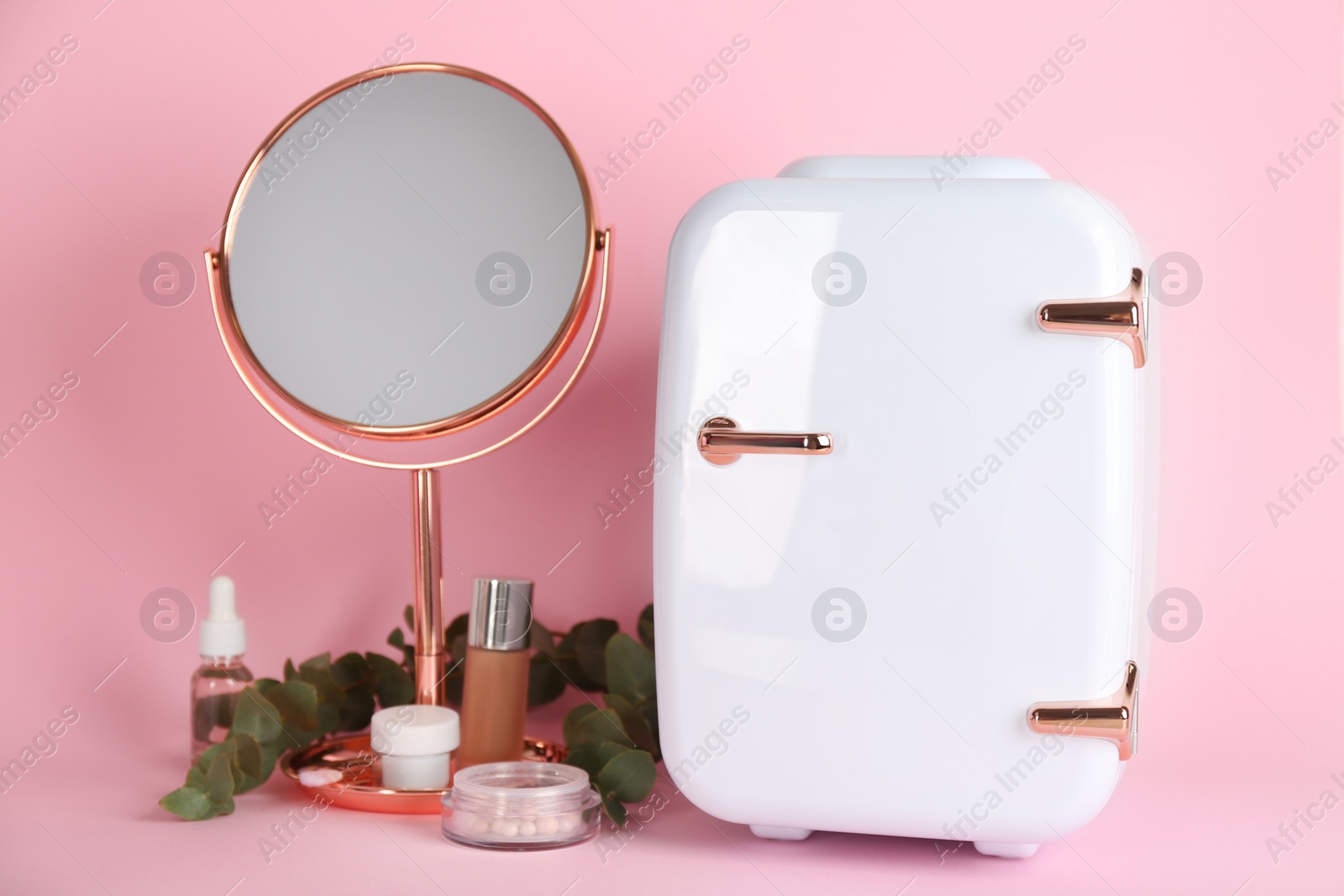 Photo of Cosmetic refrigerator and skin care products on pink background