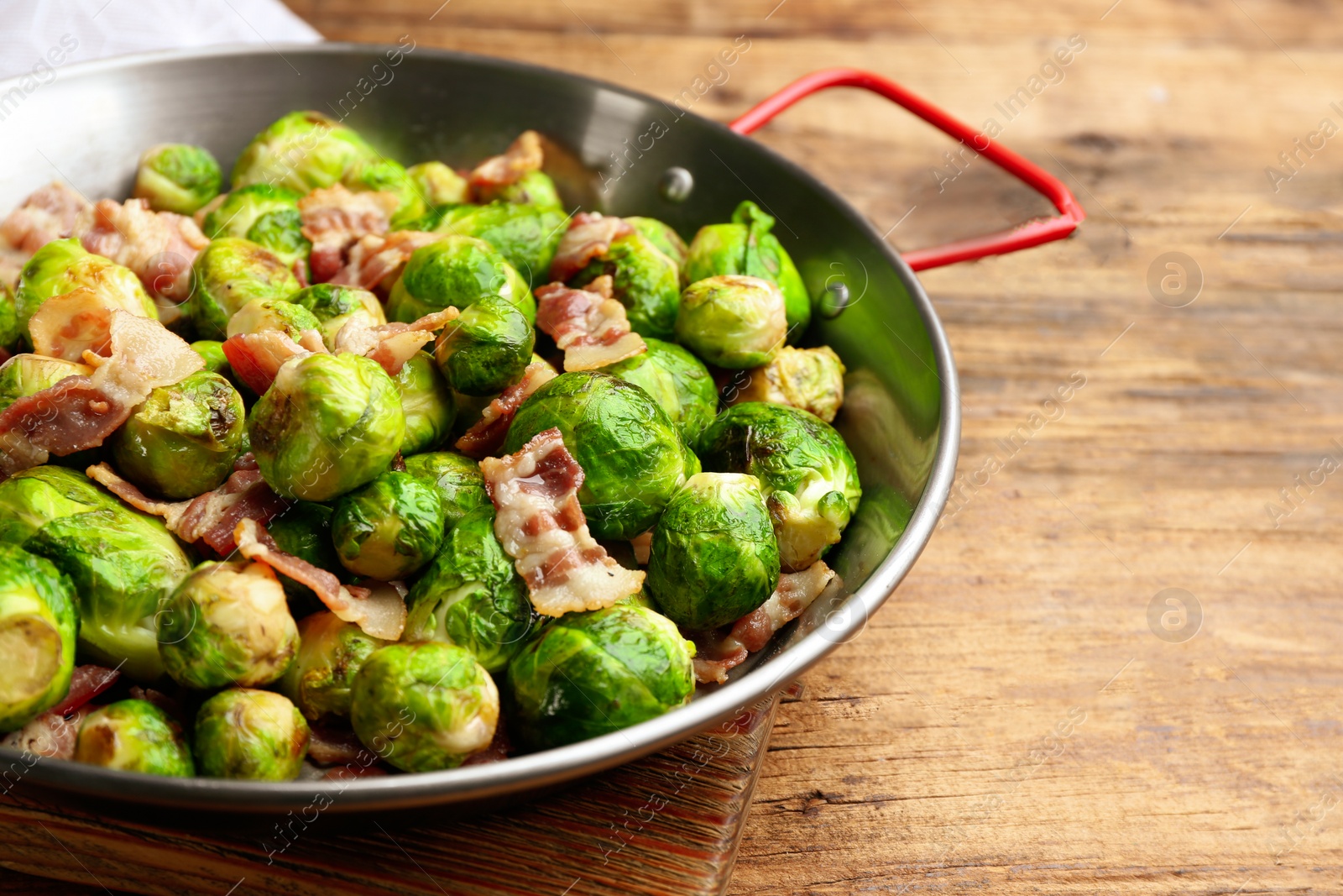 Photo of Delicious Brussels sprouts with bacon on wooden table, closeup