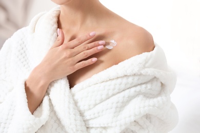 Photo of Young woman applying cream indoors, closeup. Beauty and body care