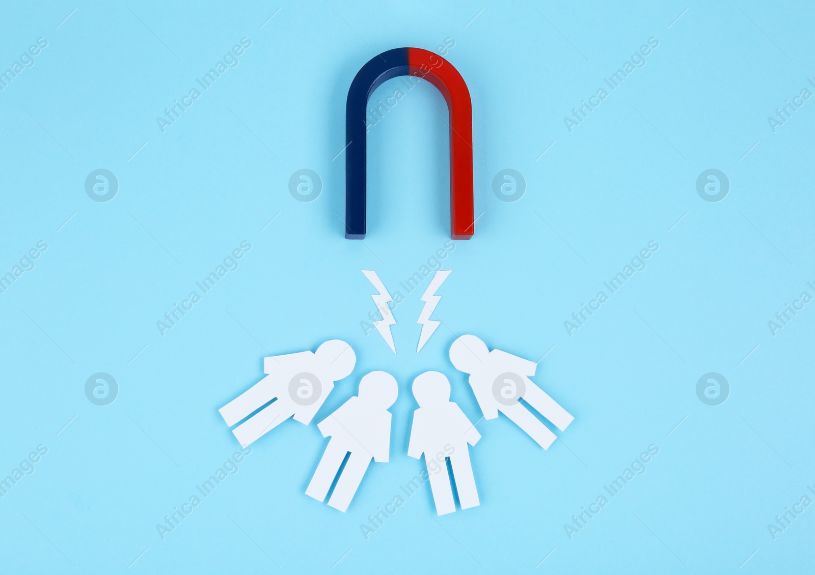 Photo of Magnet attracting paper people on light blue background, flat lay