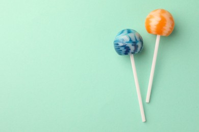 Photo of Tasty lollipops on turquoise background, flat lay. Space for text