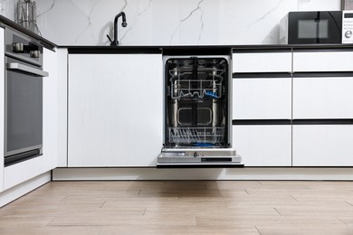 Photo of Open clean empty dishwasher in kitchen. Home appliance