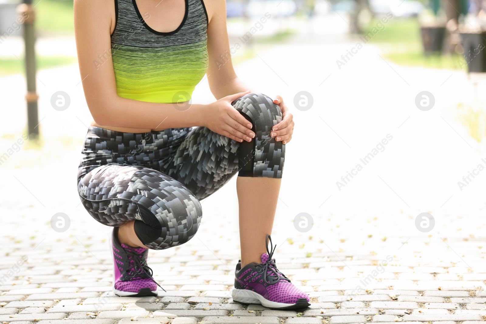 Photo of Woman in sportswear suffering from knee pain outdoors