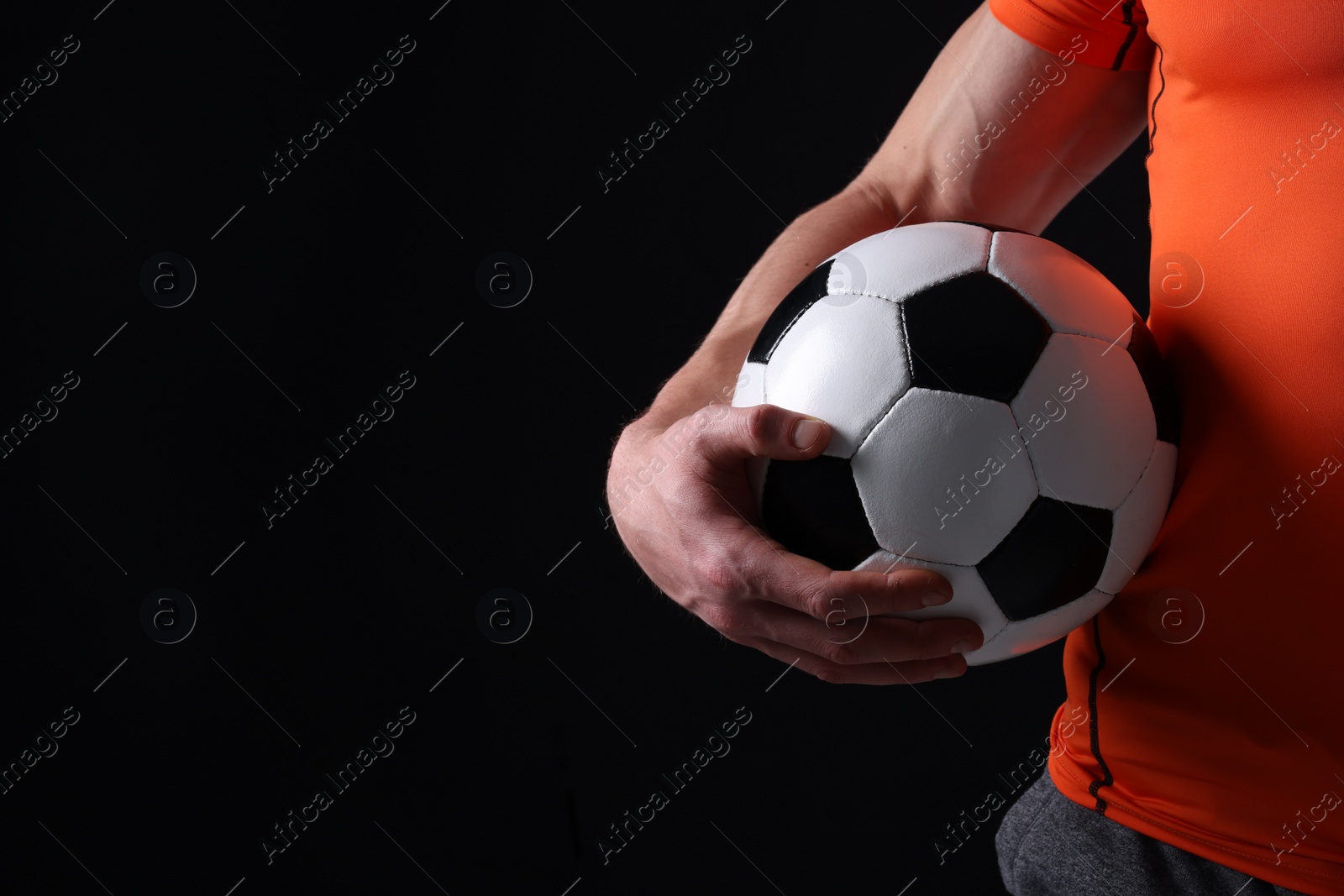 Photo of Athletic man with soccer ball on black background, closeup. Space for text