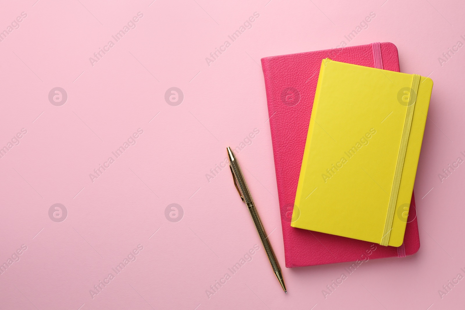 Photo of Different notebooks and pen on light pink background, top view. Space for text