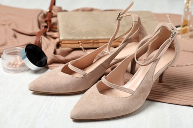 Photo of Beige suede shoes, cosmetics and accessories on white wooden table