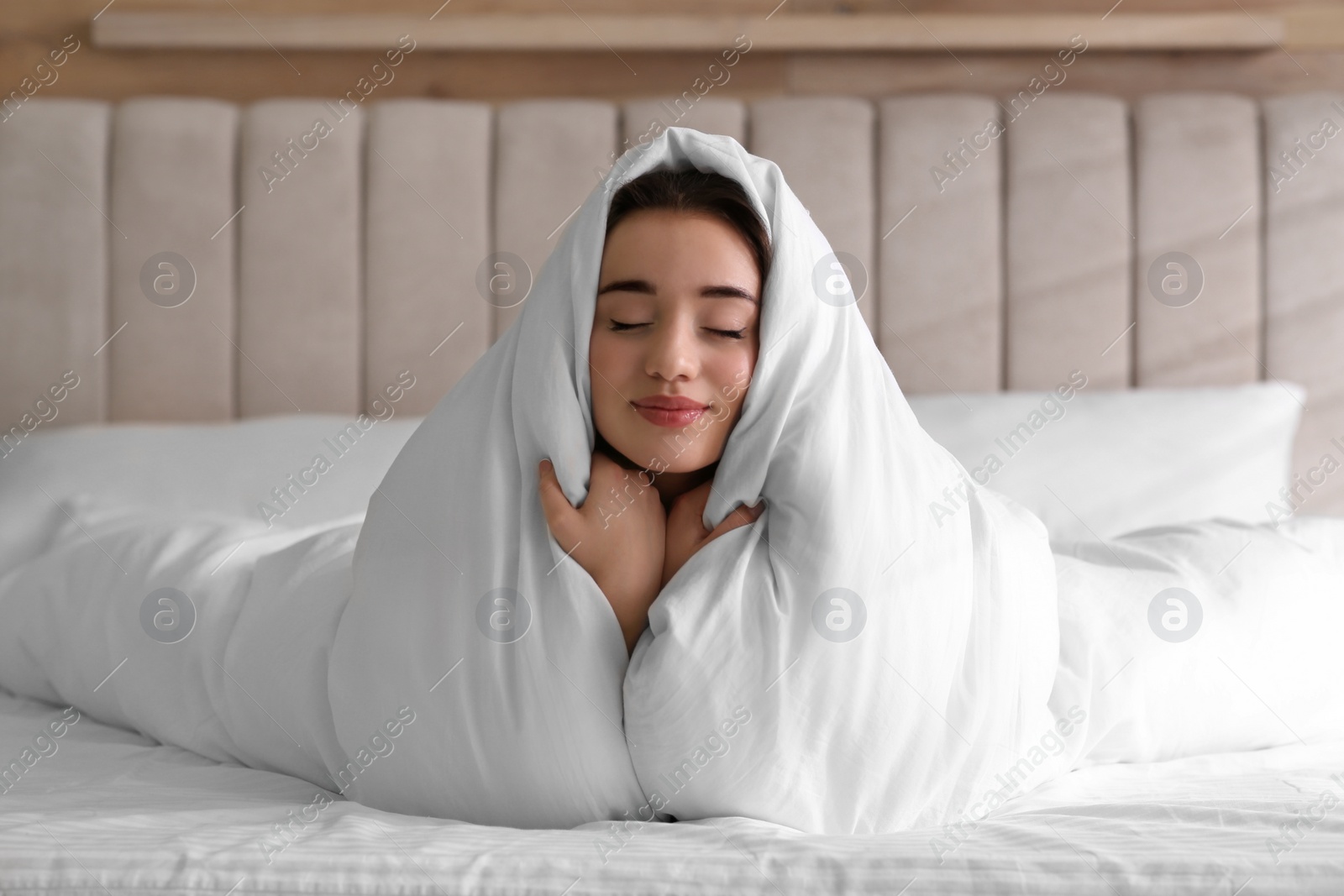 Photo of Beautiful young woman covered with warm blanket on bed at home