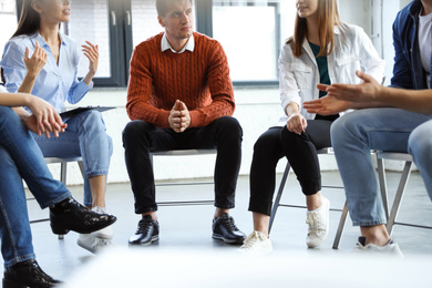 Photo of Psychotherapist working with patients in group therapy session indoors