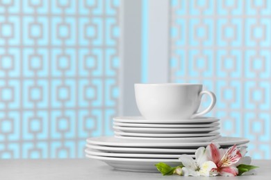 Set of clean dishware with flowers on light grey table, space for text