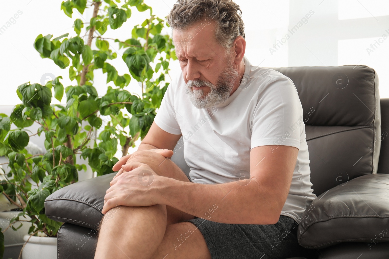 Photo of Senior man suffering from knee pain indoors